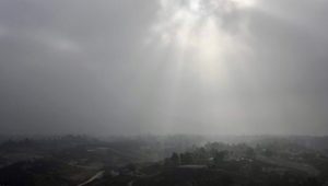sunlight shining through thick clouds over hazy town